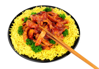 Chinese sweet and sour pork with rice on a black plate isolated on a white background