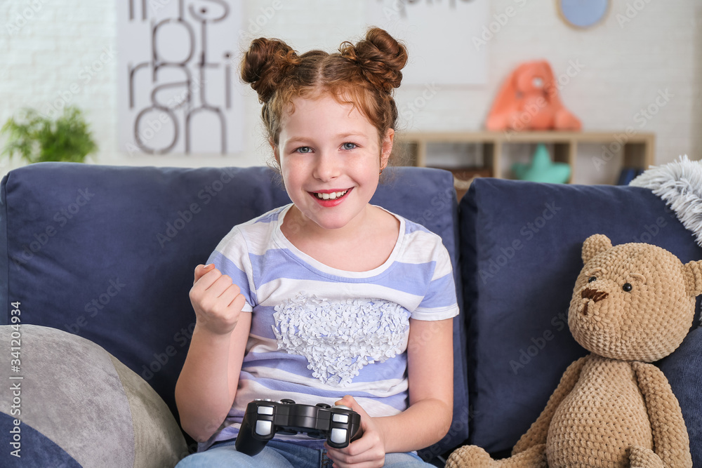 Cute little girl playing video game at home