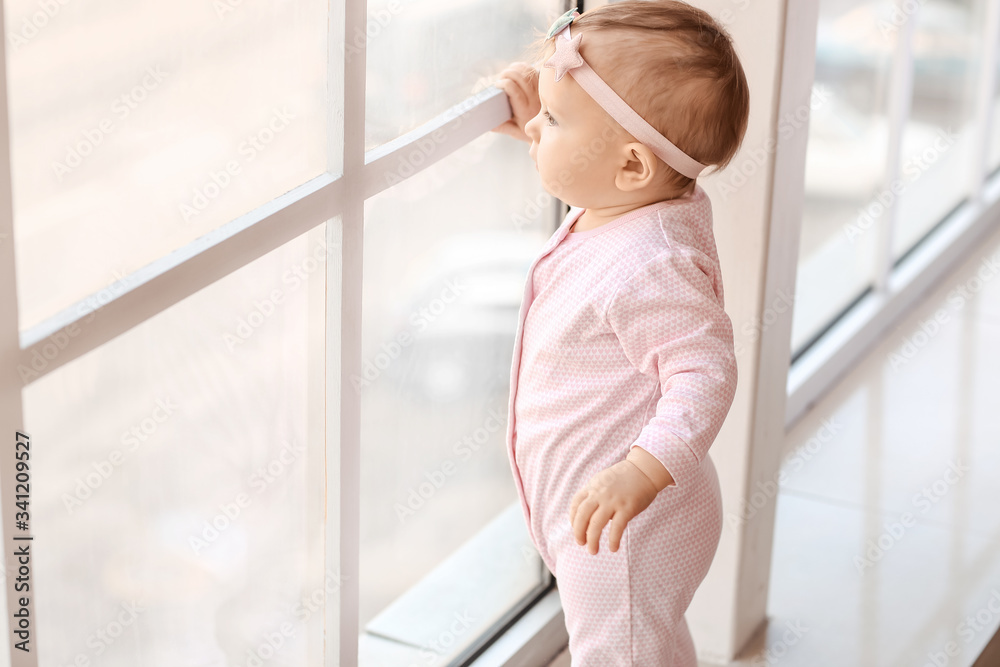 Little baby near window at home. Child in danger