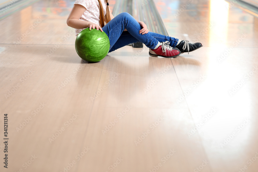 Little girl playing bowling in club