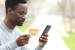 © PheelingsMedia - Black man paying with credit card on phone in a park