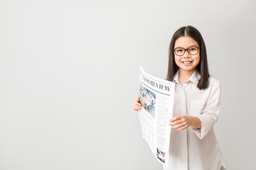 Wall Mural - Cute little businesswoman with newspaper on grey background