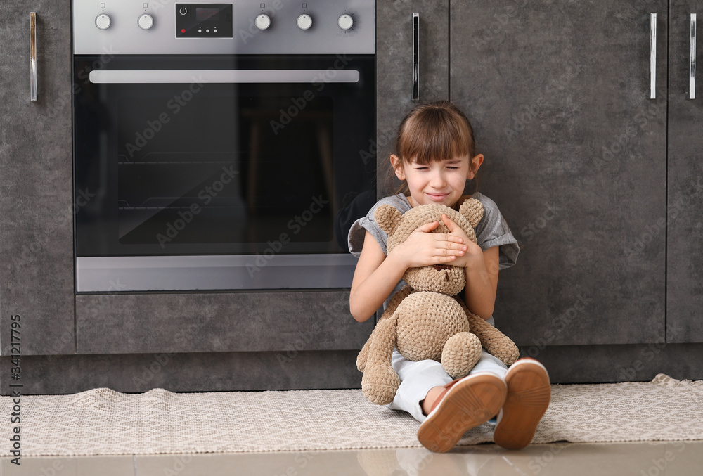 Afraid little girl with teddy bear at home. Concept of domestic violence