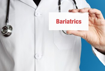 Bariatrics. Doctor in smock holds up business card. The term Bariatrics is in the sign. Symbol of disease, health, medicine