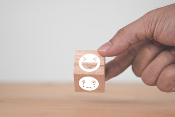Poster - Customer hand flipping happy  and smile face emotion which print screen on wooden block on sad emotion face. Customer service evaluation and copy space concept.