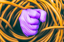 Full Frame Shot Of Tangled Yellow Cable With Purple Hand