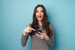 © Drobot Dean - Photo of excited nice woman smiling and pointing finger at cellphone