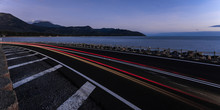 Light Trails On Road By Sea Against Clear Sky