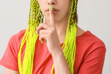 Wall Mural - Young transgender woman showing silence gesture on light background