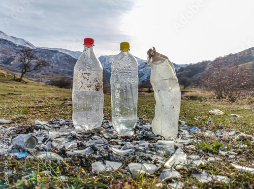 Plastic and glass trash on the background of mountains and sky. Ecological disaster. Clogging of the environment with human waste products.