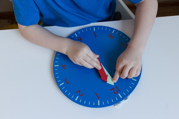 Child learns time on toy blue wood clock