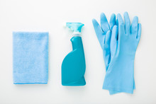 Blue Bottle, Rag, Rubber Protective Gloves On White Table Background. Simple Cleaning Set For Different Surfaces In Kitchen, Bathroom And Other Rooms. Top Down View. Closeup. Regular Cleanup.