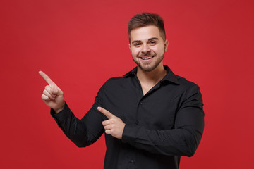 smiling young bearded guy 20s in classic black shirt posing isolated on red background studio portra