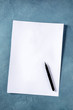 © laplateresca - A blank sheet of A4 paper with an ink pen, shot from the top on a blue background, a mockup