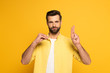 © LIGHTFIELD STUDIOS - Bearded man showing letters while using deaf and dumb language on yellow background