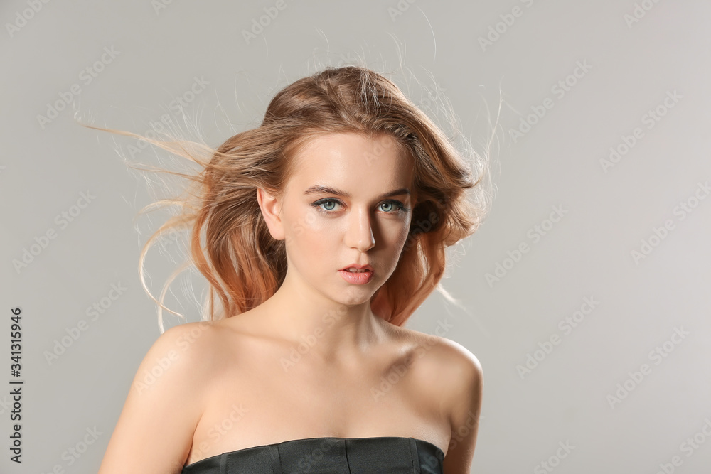 Young blonde with beautiful hair on grey background