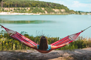 Wall Mural - woman laying on hammock enjoying the view of summer lake
