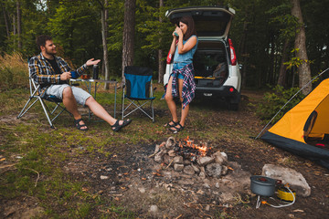 Wall Mural - couple sitting in portable chairs drinking tea talking. camping summer activities