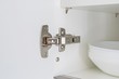 A fitted door hinge inside a white kitchen cupboard 