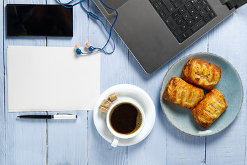 Poster - Laptop with cup of coffee and bakery on light blue old wooden table. Notebook with cup of fresh coffee in home office. Working from home concept