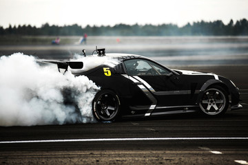 
a sports car drifts tires on asphalt on a racetrack