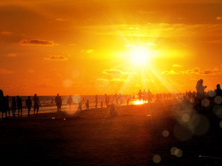 Poster - group of silhouetted people on public beach over orange colored sunset sky in Siesta key, Sarasota, Florida