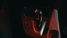 the man in the car puts hand the gear selector into drive mode