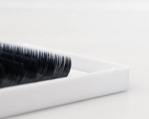 A close up image of a tray or black lash extensions in a white box and against a white background 