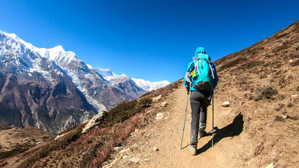 a man trekking on the annapurna circuit trek, himalayas, nepal. panoramic view on snow caped annapur