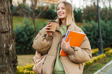 Poster - Portrait of woman drinking coffee takeaway while walking in park