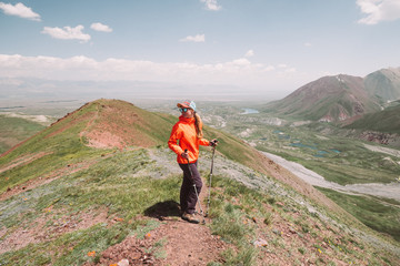 Wall Mural - Pamir. Mountains against the blue sky. Sunny weather. A girl in the mountains in sportswear stands and looks into the distance. Smiles