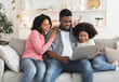 © Prostock-studio - Loving African American Family Of Three Resting On Couch With Laptop