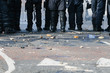 Stones and bricks litter the road as police riot squad move forward after a crowd riots