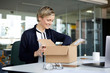 © Westend61 - Smiling businesswoman unpacking parcel on desk in office