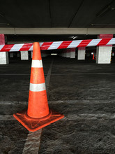 An Orange Traffic Cone And Red And White Tape. It's "no Entry" Sign Put On Concrete Floor With White Line At Empty Car Park.