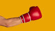Closeup of sportsman wearing boxing glove on orange background, panorama