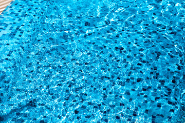 Shining blue water background with ripples modern fashionable swimming pool lined with white and blue Venetian mosaic tiles