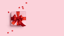 Pink Gift Box With Red Bow On Pink Background With Red Hearts Around. Holiday Web Banner. Top View. Flat Lay. Copy Space