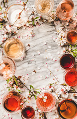 Various shades of Rose. Flat-lay of Rose wine of different colors in glasses and spring blossom flower over white background, top view, copy space. Wine shop, bar, wine tasting, wine list concept