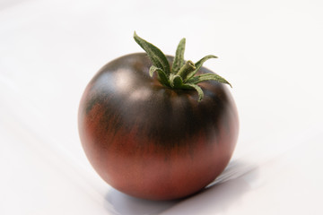 A perfectly colored Cherokee Red Tomato on a white background. 