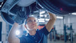 © Gorodenkoff - Portrait Shot of a Female Mechanic Working Under Vehicle in a Car Service. Empowering Woman Wearing Gloves and Using a Ratchet Underneath the Car. Modern Clean Workshop.