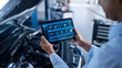 © Gorodenkoff - Car Service Manager or Mechanic Uses a Tablet Computer with a Futuristic Interactive Diagnostics Software. Specialist Inspecting the Vehicle in Order to Find Broken Components In the Engine Bay.