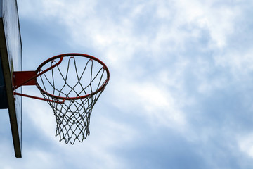 Wall Mural - Dark silhouette of street basketball hoop an a cloudy day. Close up of hoop net. Urban youth game