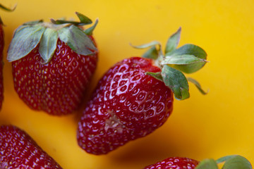 juicy red strawberries lies on a yellow background
