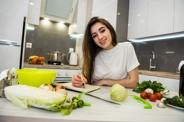 Young woman cooking  food using a notepad as help in her kitchen