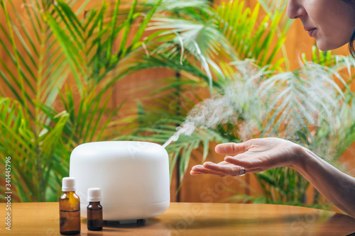 Fotografía Woman Enjoying Aroma Therapy Steam Scent from Home Essential Oil Diffuser or Air
