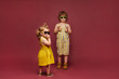 Cute stylish children in fashionable clothes posing on pink background. A little girl in a dress and sunglasses and a boy in a summer stylish overalls and sunglasses