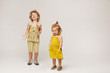 Two cute stylish children, boy and girl in fashionable summer clothes posing on a beige background. Isolated in full length with copy space