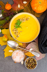 Wall Mural - Hot pumpkin soup on background of dried autumn leaves.