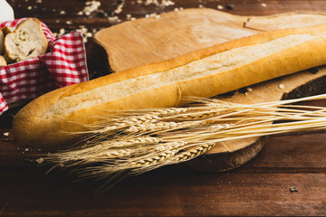 Fresh bread and wheat on wood